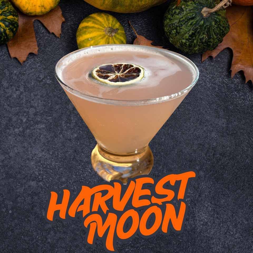 Peach-colored cocktail garnished with a dried citrus wheel, surrounded by autumn leaves and gourds, with “Harvest Moon” text below.